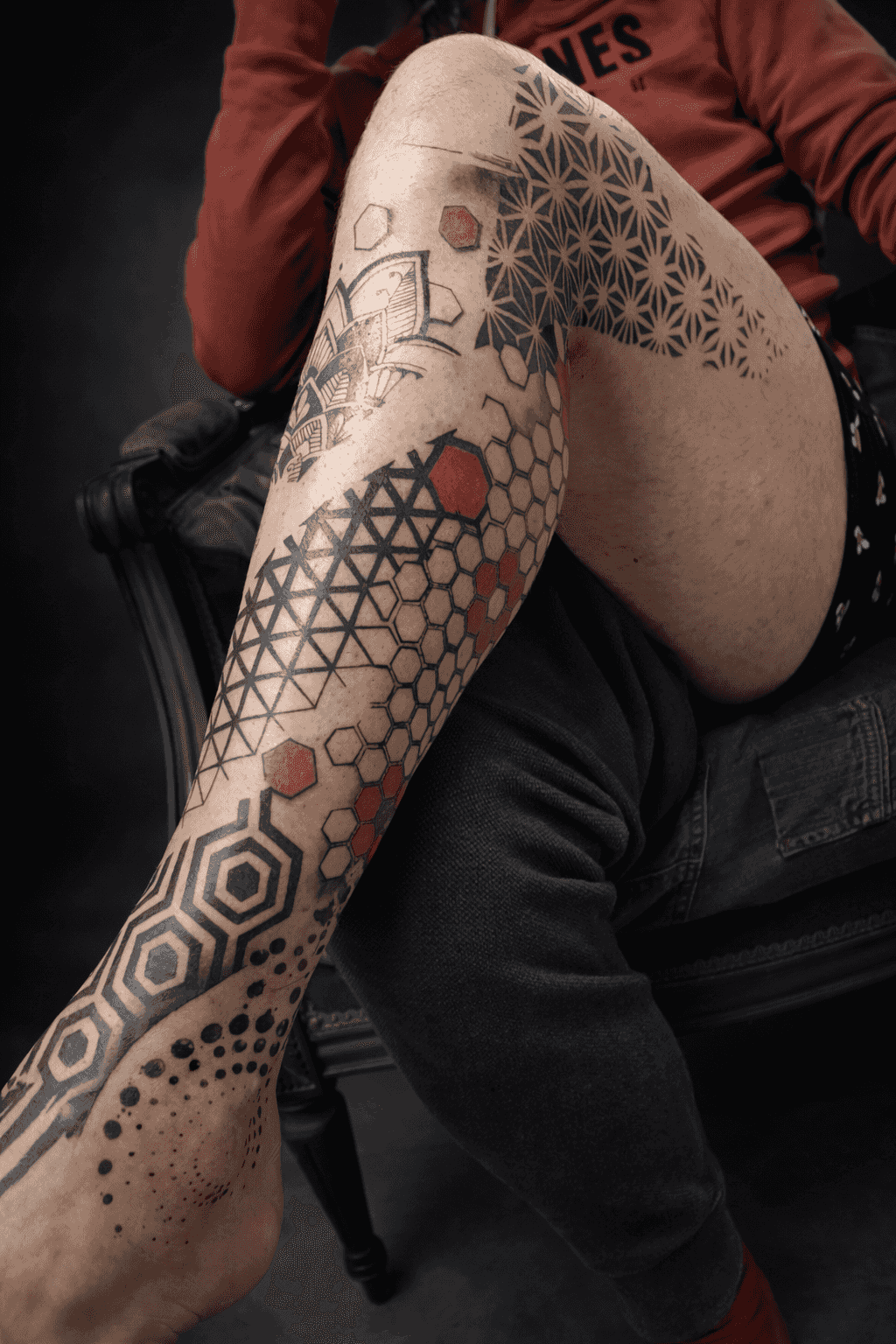 tatouage de motifs géométriques noir et rouge sur une jambe