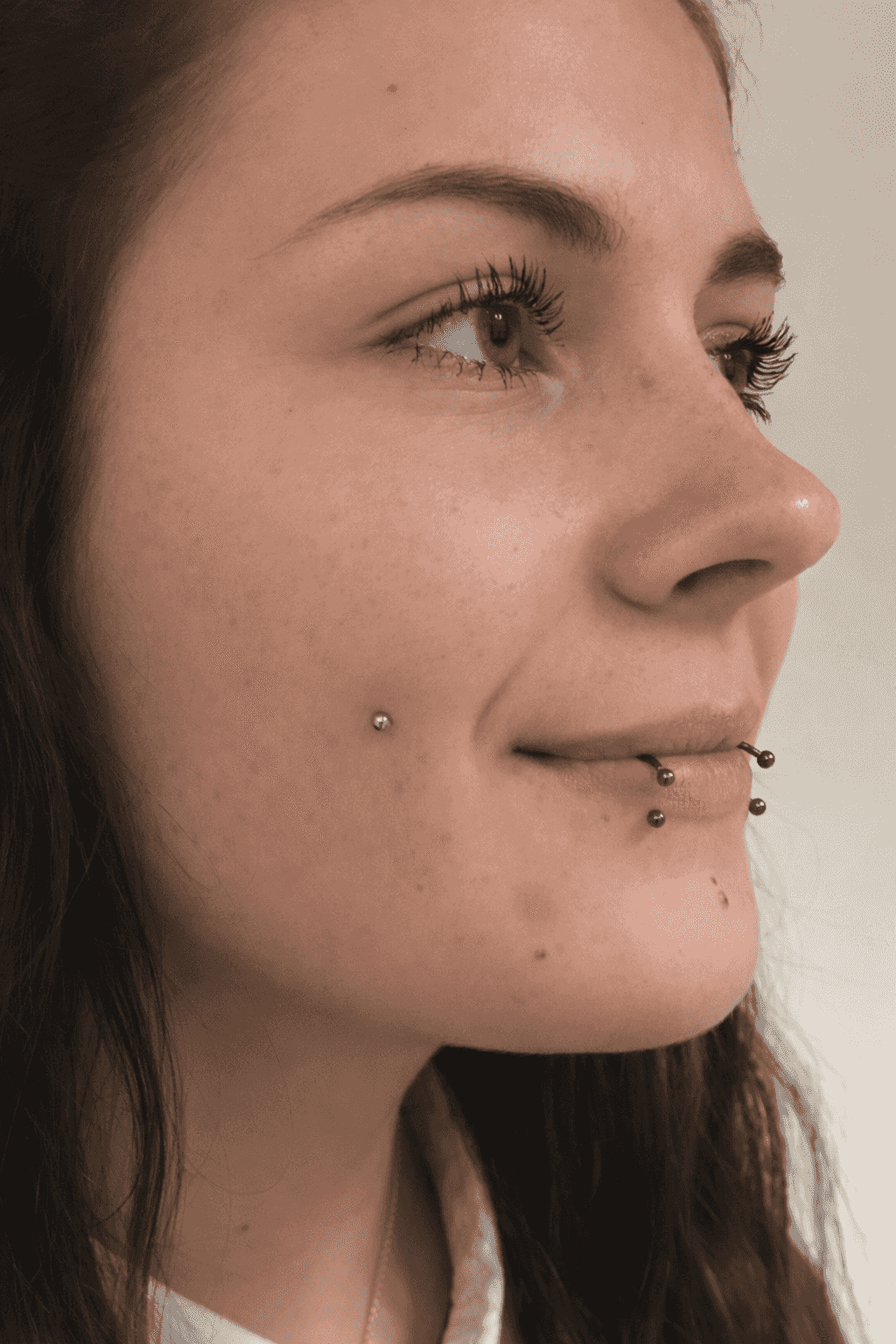 femme avec un piercing dolphin bites et un microdermal dans la joue gauche